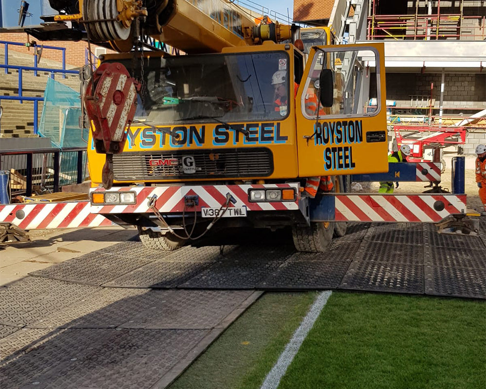 Yellow crane truck with 'Royston Steel' branding on a construction site.