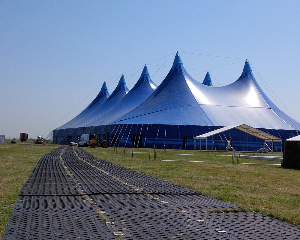 Large blue tent structure on a grassy field with clear sky