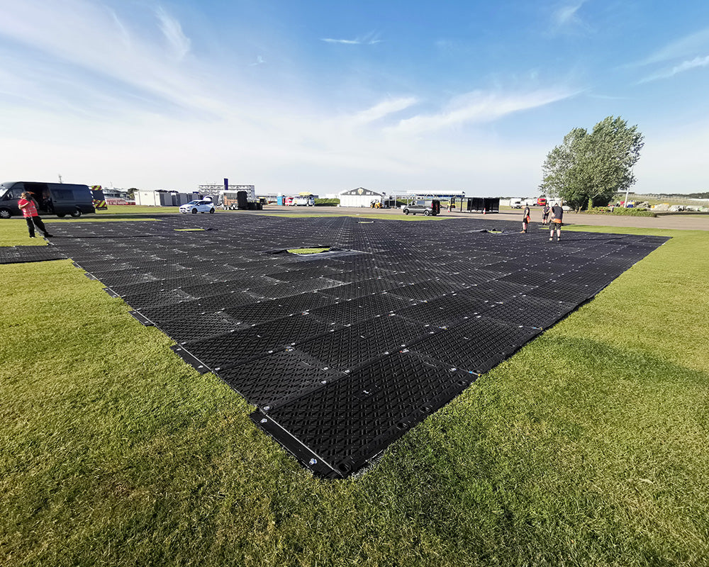 Large black grid on grass with people in the background