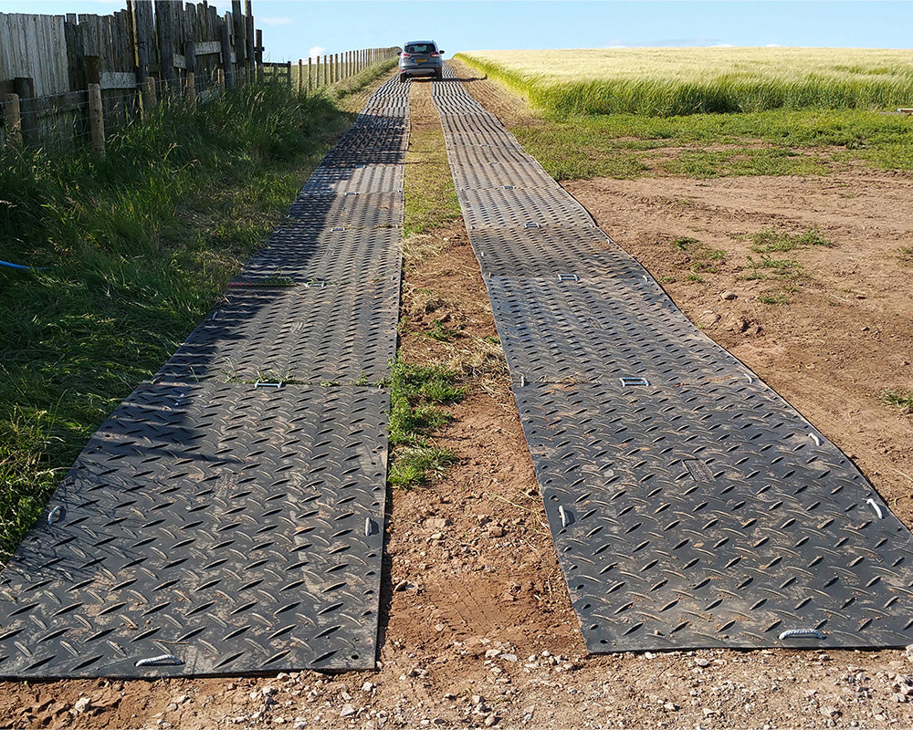 Two rows of MultiTrack mats on a dirt path with grass on either side.