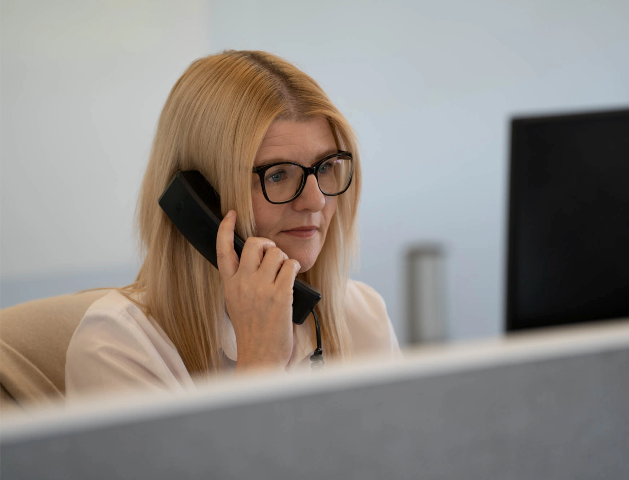 Woman with glasses talking on a phone in an office setting