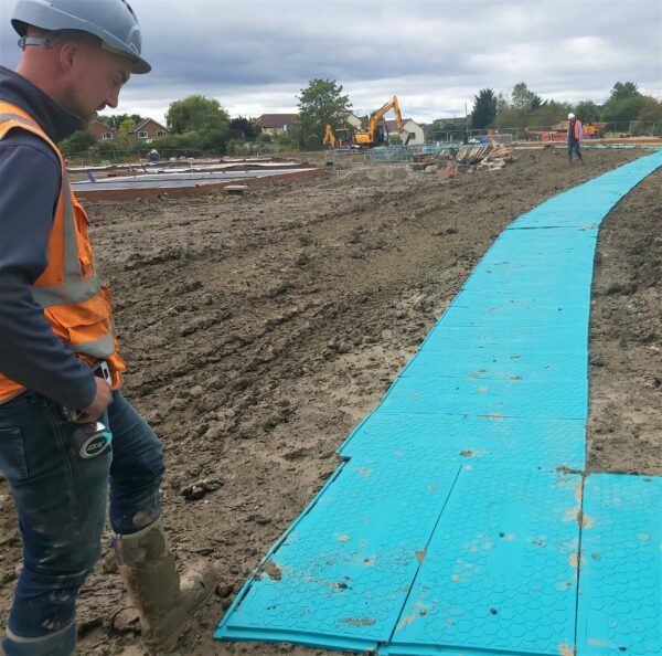 Temporary walkway across muddy field construction site